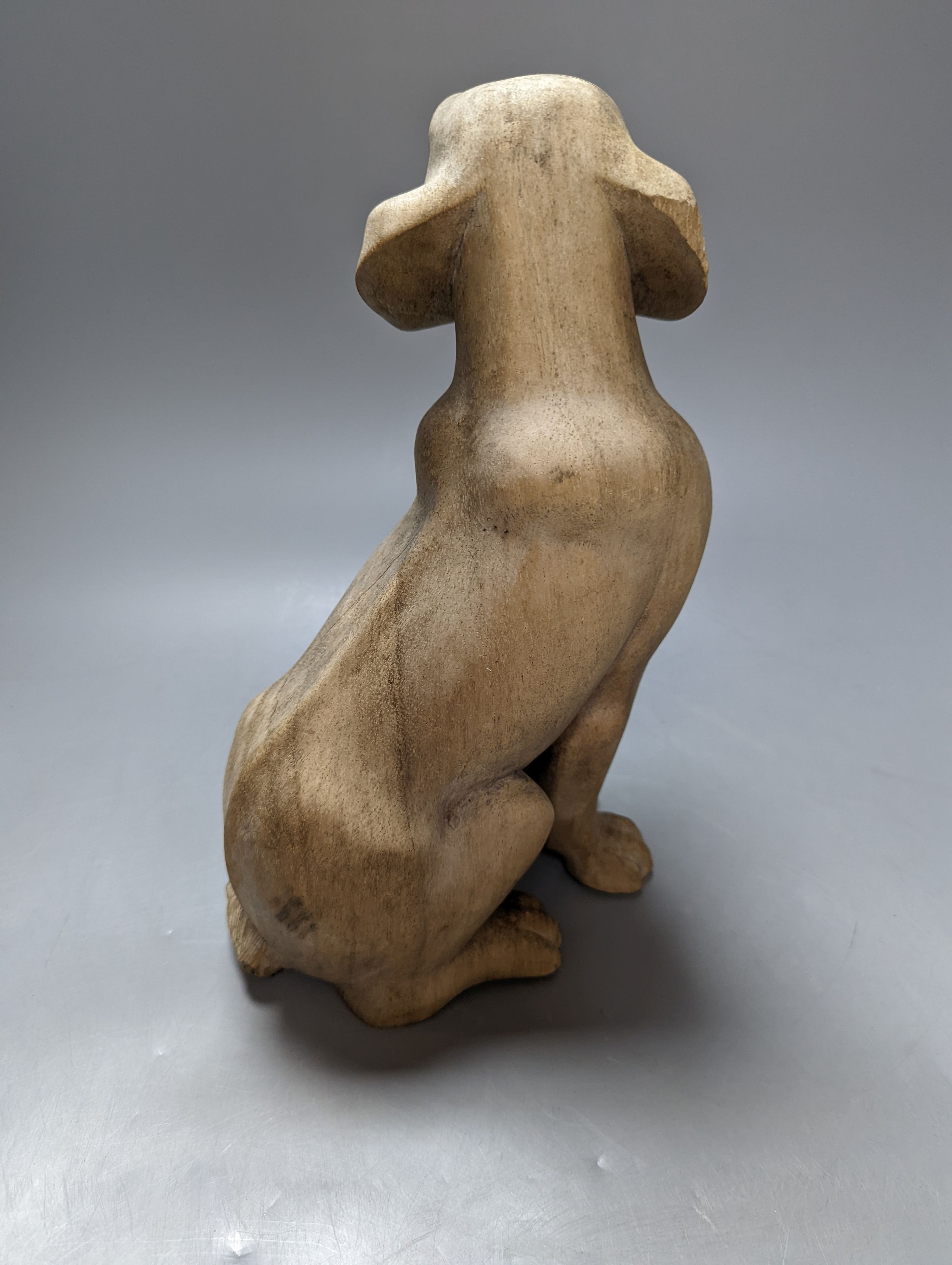 A carved wood model of a seated dog 29cm